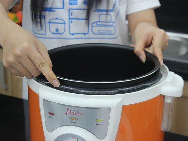Đặt lồng nồi vào nồi nấu bằng hai tay