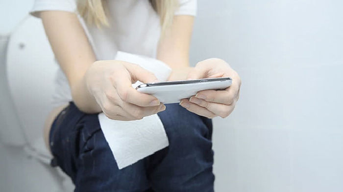 Ngồi trong nhà vệ sinh xem báo, dùng điện thoại